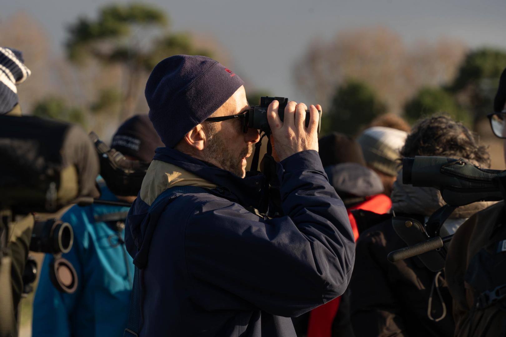 Un groupe de personnes observe les oiseaux avec des jumelles et des longues-vues.